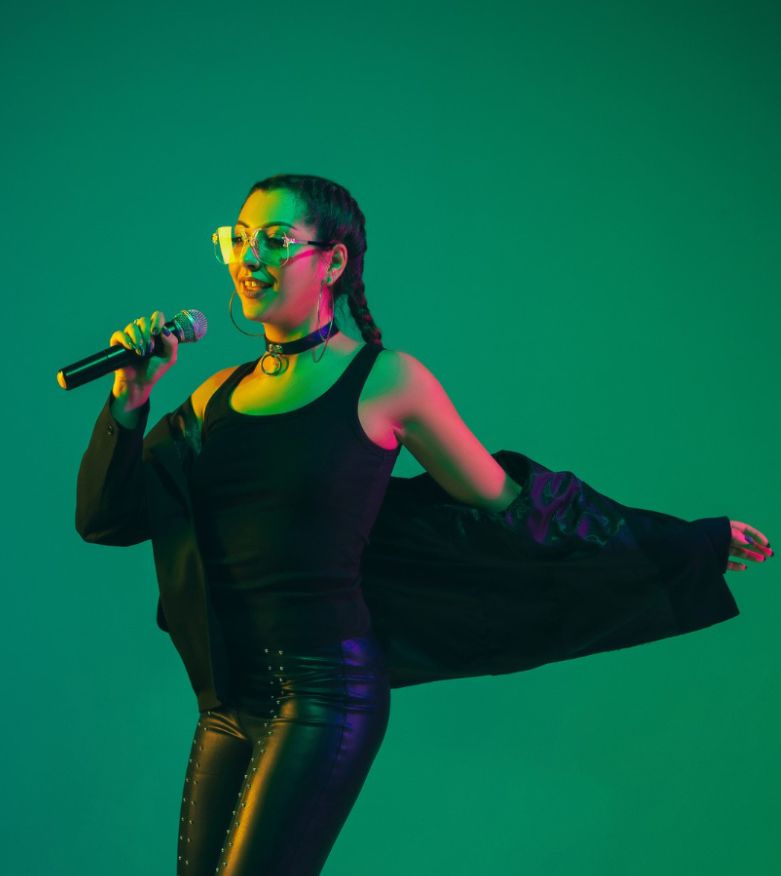 Female singer portrait isolated on green studio wall in neon light